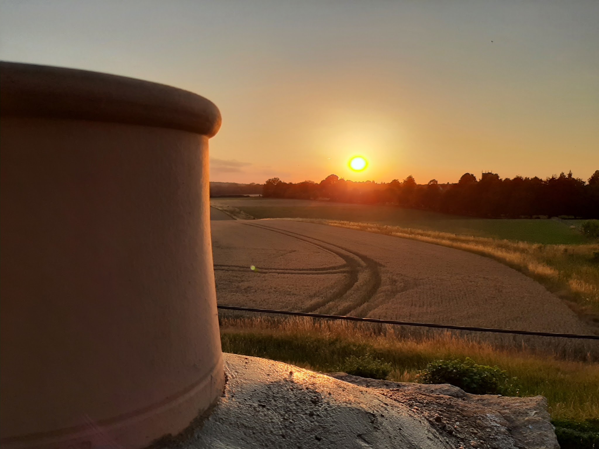 A chimney pot at sunset above Cotswold wheat fields