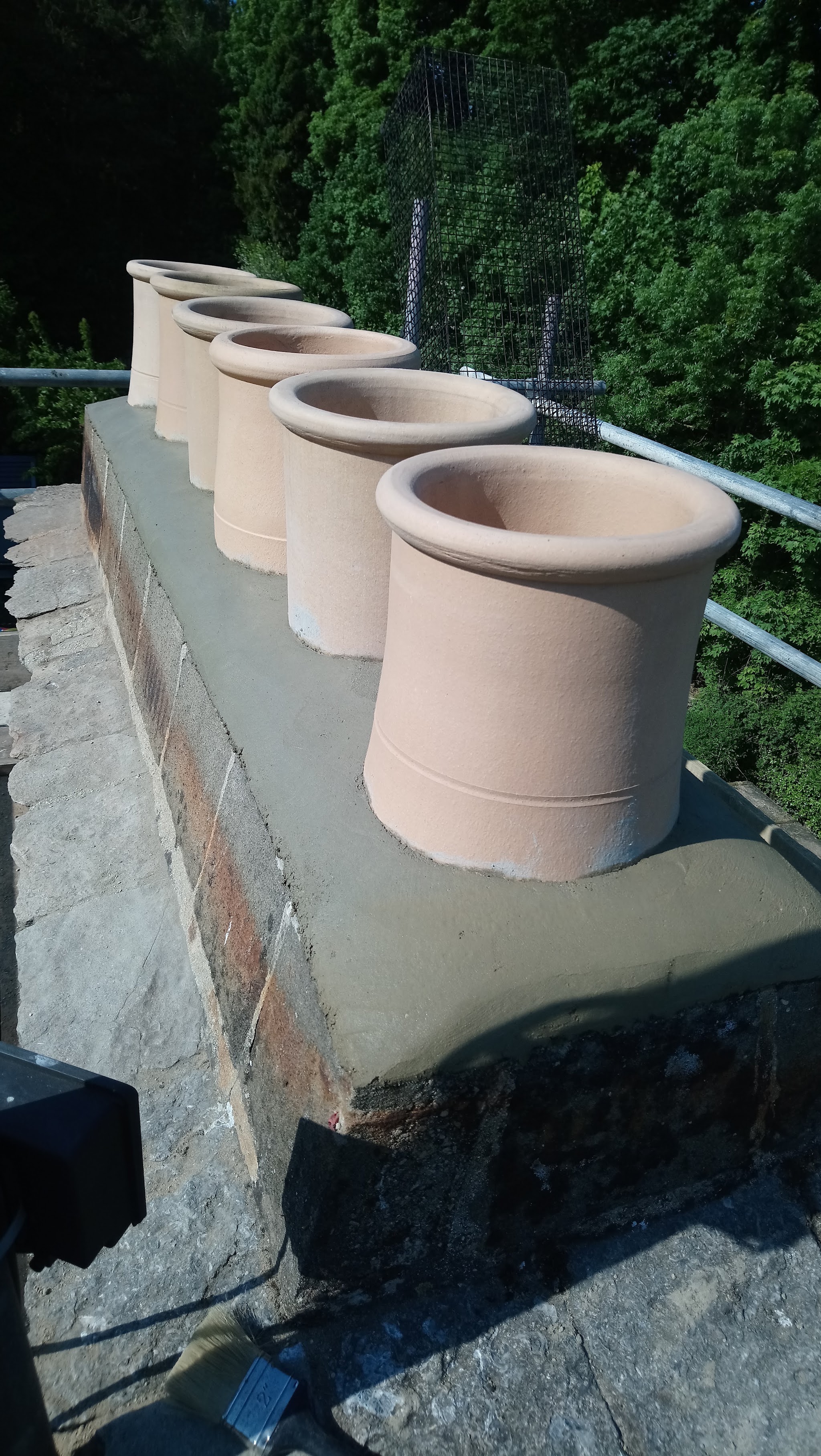 A row of six buff chimney pots set on a stone chimney stack