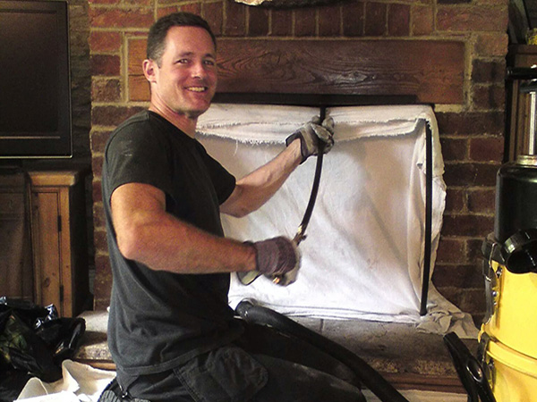 Mayn sweeping a brick fireplace with a dust sheet in place